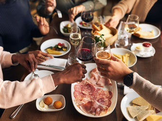 A group of friends toast glasses of wine over a casual dinner table