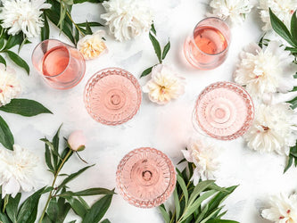 Glasses of rosé wine, surrounded by flowers and greener, shot from above